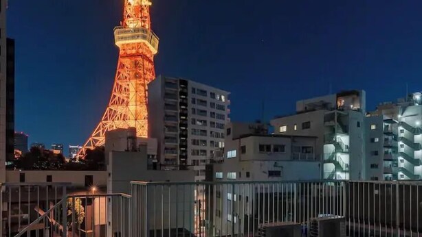 Una terrazza sul tetto con arredi da esterno e vista illuminata sulla Tokyo Tower di notte.