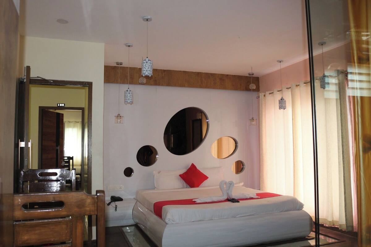 Ein Hotelzimmer mit einem Bett, einem Schreibtisch, einem Spiegel und einer Wand mit runden Spiegeln sowie einem großen ovalen Spiegel.