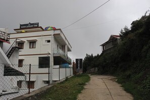A building with a sign for "Kasa Luxury Inn" and a colorful umbrella on the roof. - Kasa Luxury INN (Kodaikanal)