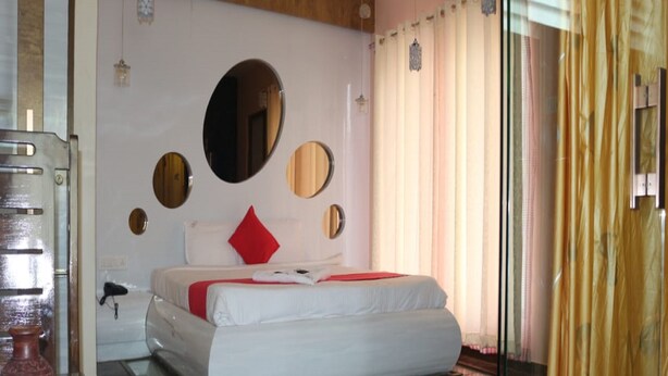Une chambre moderne avec un grand lit, une table de chevet, un miroir et une fenêtre avec des rideaux.