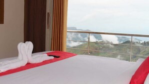 Une chambre d’hôtel avec un lit, une couverture rouge et une vue sur un paysage montagneux.