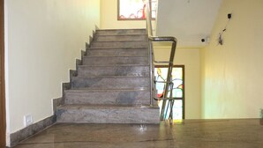 Un escalier avec une rampe métallique menant à une porte ornée d’un vitrail.