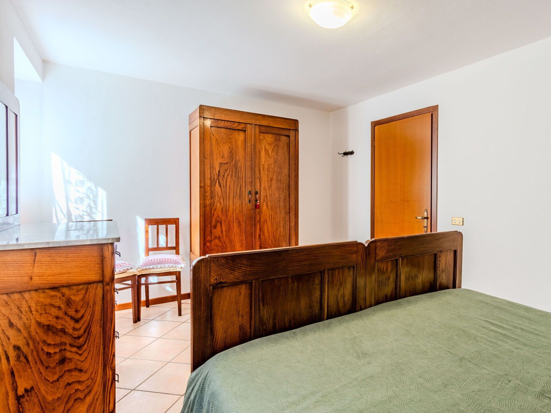 Ein Schlafzimmer mit einem Bett, einem Holzschrank und einem Sessel.