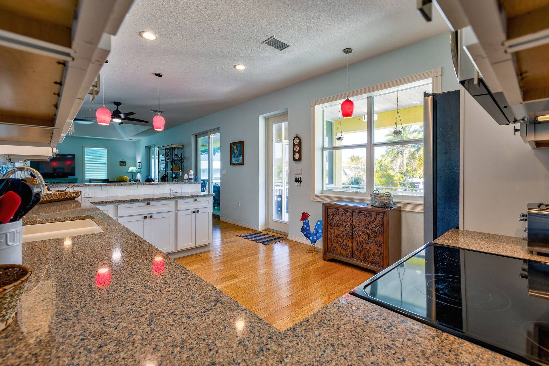 A modern kitchen with granite countertops, a black stove, and a window with a view of palm trees.