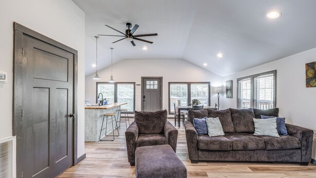 A spacious living room with a dark brown sofa set, a matching ottoman, and a ceiling fan. - 2 Mi to Warm Springs Pools: Home w/ Large Yard! (Warm Springs)