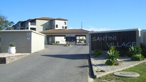 Une entrée fermée par un portail mène au village de Santini, et une allée pavée conduit à un bâtiment surmonté d’un toit en tuiles.