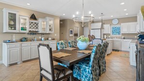 A modern kitchen with white cabinetry, a dining area with patterned chairs, and a chandelier. - Catalina Lakeside Retreat: Lakefront, Dock Access, Grill, Views, and Near Hot Springs National Park! (Hot Springs)