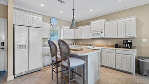 A kitchen with white cabinets, a refrigerator, a sink, a coffee maker, and two wooden chairs. - Catalina Lakeside Retreat: Lakefront, Dock Access, Grill, Views, and Near Hot Springs National Park! (Hot Springs)