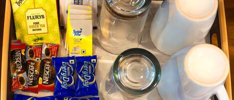 Uma bandeja com diversos produtos de café e chá, incluindo Nescafe e Flurys, e duas canecas brancas.