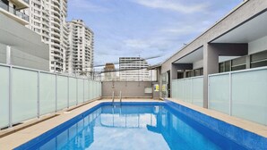 A rectangular indoor swimming pool with clear blue water, surrounded by glass walls and a metal railing. - Studio3: Chic Bondi Abode with Pool & A/C (Bondi Junction)