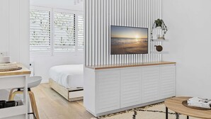 A modern bedroom with a bed, a desk, and a wall-mounted TV. - Studio3: Chic Bondi Abode with Pool & A/C (Bondi Junction)