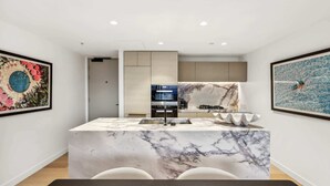 Een moderne keuken met een marmeren eiland, inbouwapparatuur en kunst aan de muren.