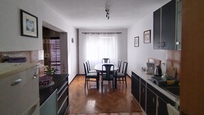 Una cocina compacta con comedor, que incluye una mesa central con sillas, horno empotrado y lavamanos.
