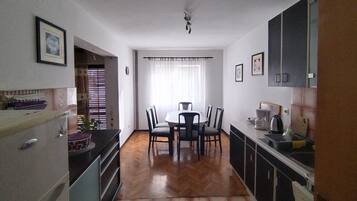 Een compacte keuken met een eethoek, met een centrale tafel met stoelen, een inbouwoven en een spoelbak.
