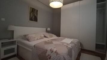 Une chambre à coucher comprenant un lit, des tables de chevet, un luminaire suspendu, une armoire et un tableau accroché au mur.