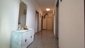 Un pasillo con un aparador blanco, un espejo y una puerta al final.