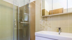 A bathroom with a glass shower enclosure, a white sink, and a mirror above the sink.
