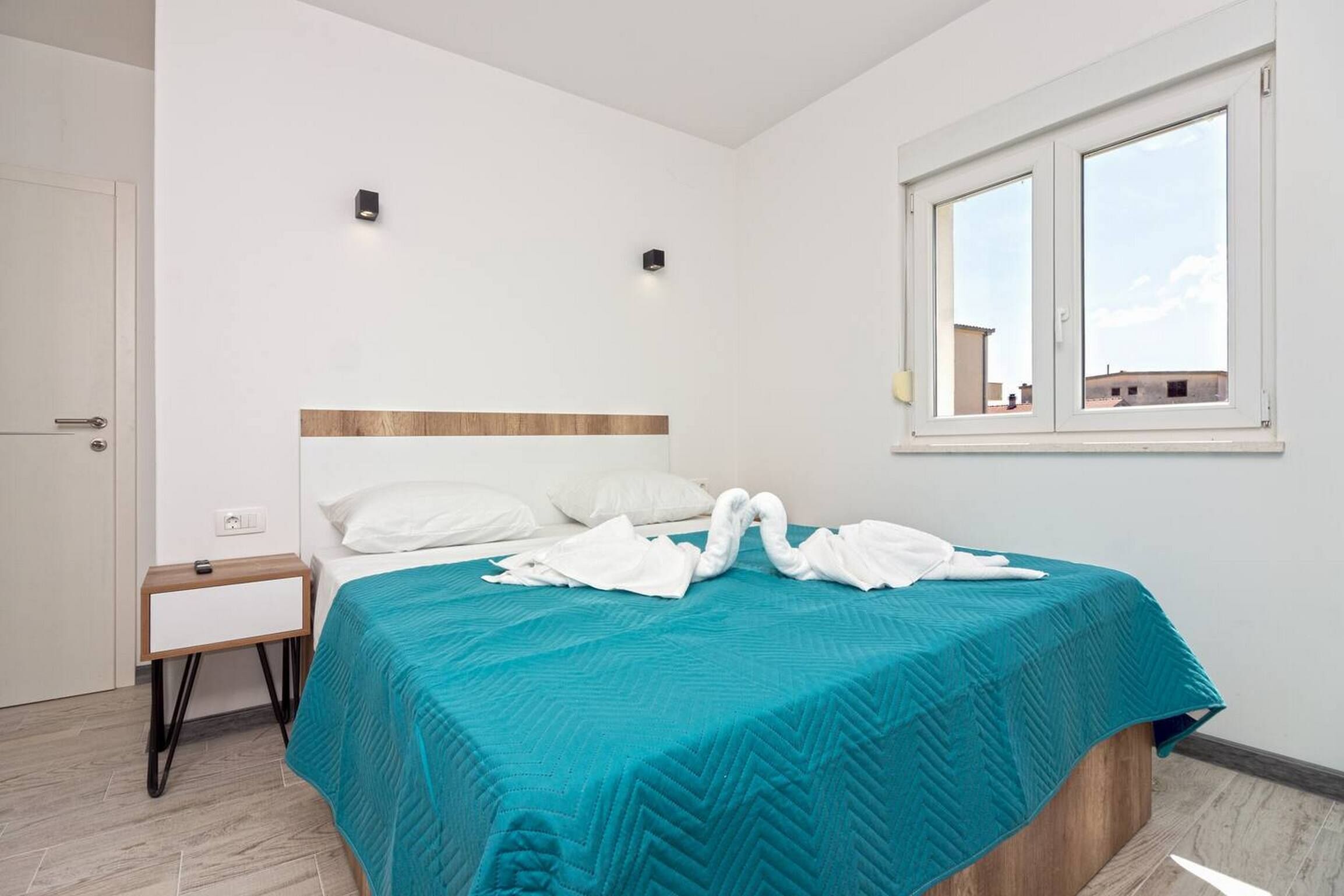 Une chambre à coucher avec un lit, une table de chevet, une fenêtre et une vue sur l’extérieur.