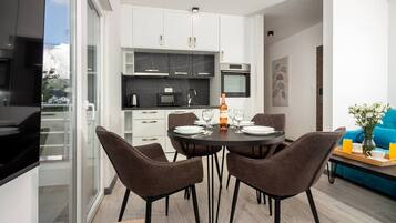 A modern kitchen with white cabinets, a black countertop, and a dining area with a round table and four chairs.