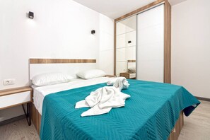 A hotel room with a bed, a nightstand, a mirror, and a wooden headboard.