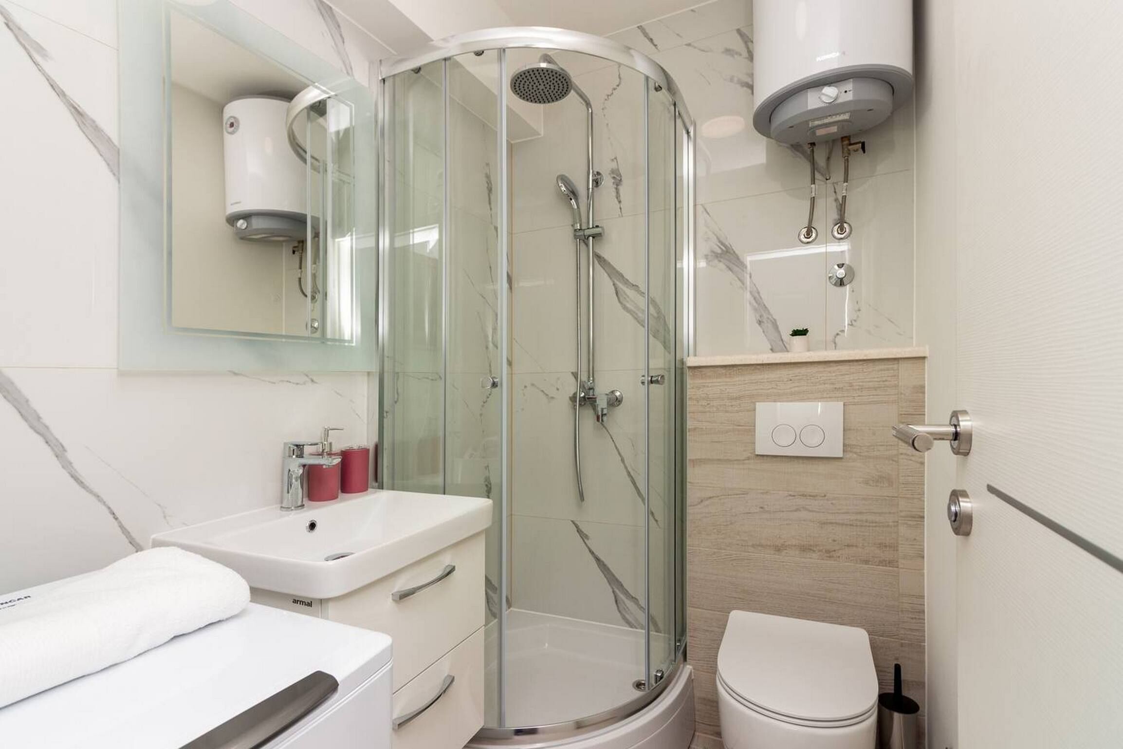 Une salle de bain moderne avec une douche à parois de verre, un lavabo blanc et des toilettes.