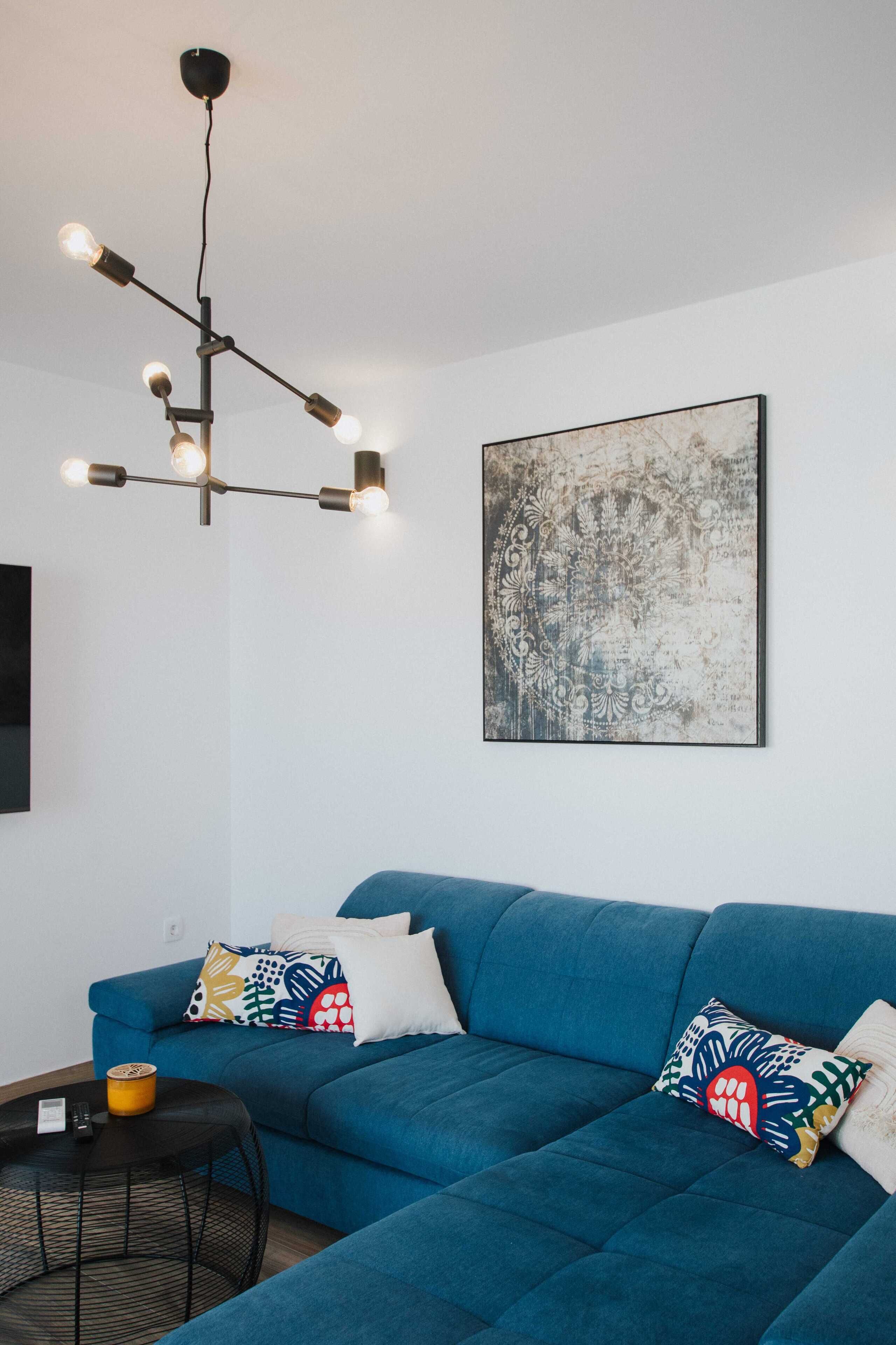 A modern living room with a blue sofa, a black coffee table, and a unique chandelier.