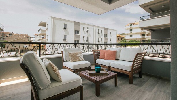 A balcony with a sofa set, a wooden coffee table, and a railing. - Spacious Luxury Trogir Apartments (Trogir)