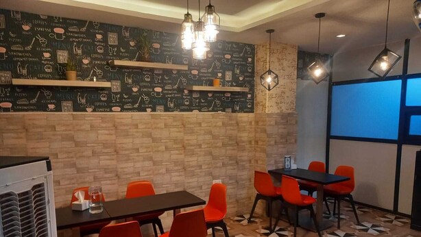 Ein Café mit einer Kreidetafel-Speisekarte, roten Stühlen und einem gemusterten Boden.