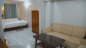 Ein Schlafzimmer mit einem Bett, einem Holzschrank, einem beigen Sofa und einem Tisch mit Marmorplatte.