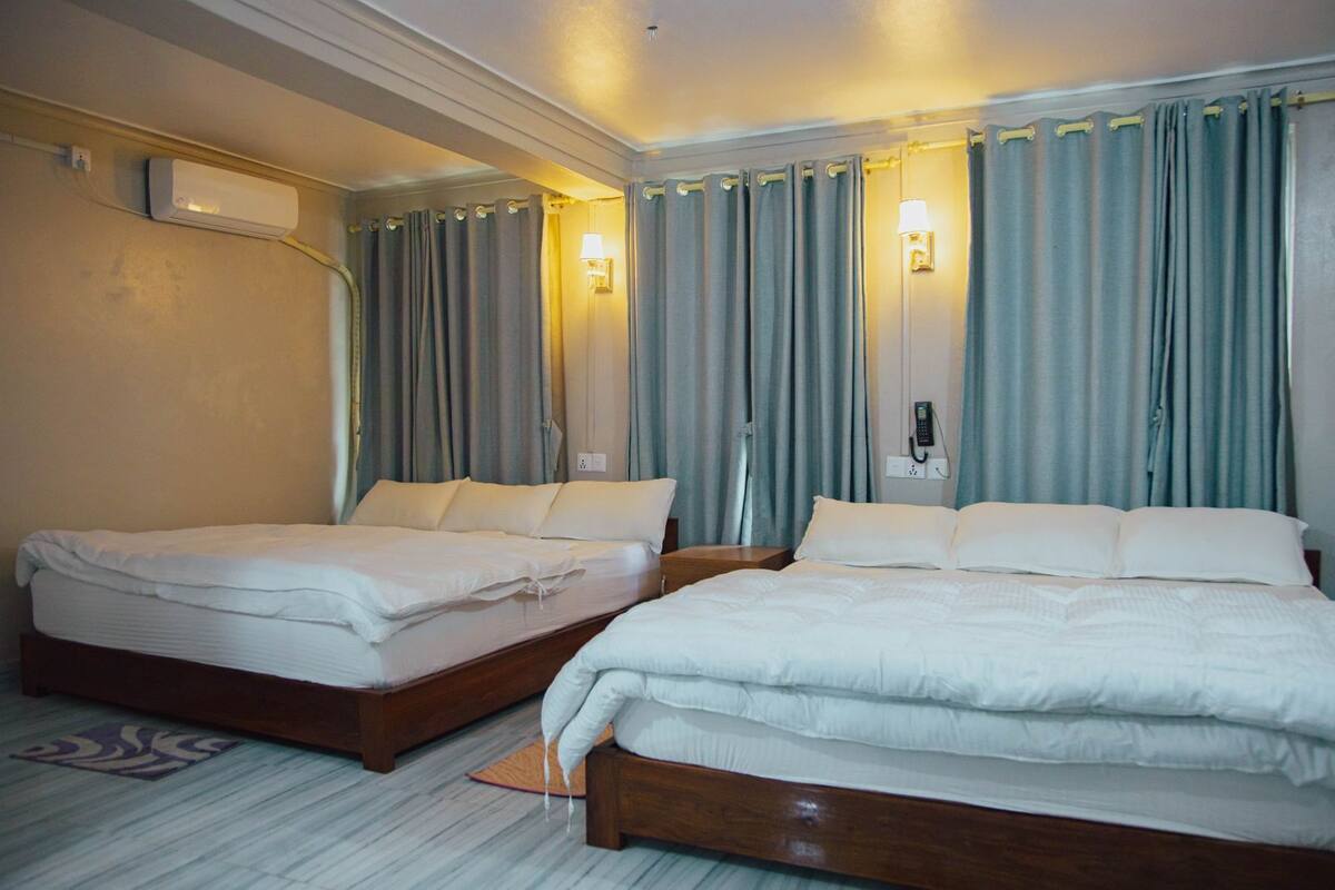 Une chambre d’hôtel avec deux lits, un climatiseur fixé au mur et un téléphone.