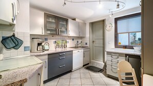 A kitchen with white cabinets, a dishwasher, a sink, and a window with blinds.