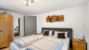 A bedroom with a bed, bedside tables, a wardrobe, a mirror, and a wall-mounted deer head decoration.