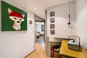 Käytävällä on seinällä laaman kuva, puinen pöytä, jonka päällä on laatikko, sekä palosammutin.