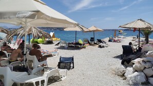 Ein Café direkt am Strand mit Terrassensitzgelegenheiten, Sonnenschirmen und Meerblick.