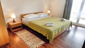 Ein ordentlich bezogenes Bett mit einer grünen Decke, zwei Nachttischlampen, einem Holznachttisch und einem gemusterten Teppich.