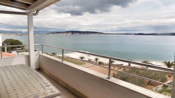 Ein Balkon mit Blick auf ein ruhiges Meer und sanfte Hügel in der Ferne.