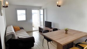 Ein modernes Wohnzimmer mit einer Couch, einem Esstisch und einem Fernseher.