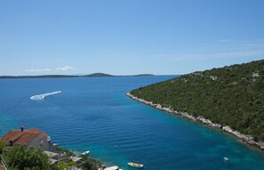 A coastal view with clear blue waters, a boat, and a small building. - Wonderful Visinisce Apartments With Terrace and Sea Views (Marina)