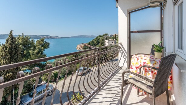 A balcony with a view of the sea, a chair, a table, and a potted plant. - Charming Trogir Apartments With Balcony (Trogir)