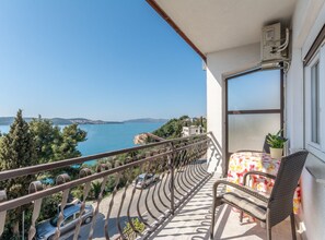 A balcony with a view of the sea, a chair, a table, and a potted plant. - Charming Trogir Apartments With Balcony (Trogir)