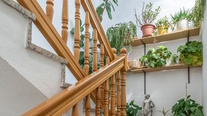 A wooden staircase with a handrail, surrounded by potted plants and a statue. - Charming Trogir Apartments With Balcony (Trogir)