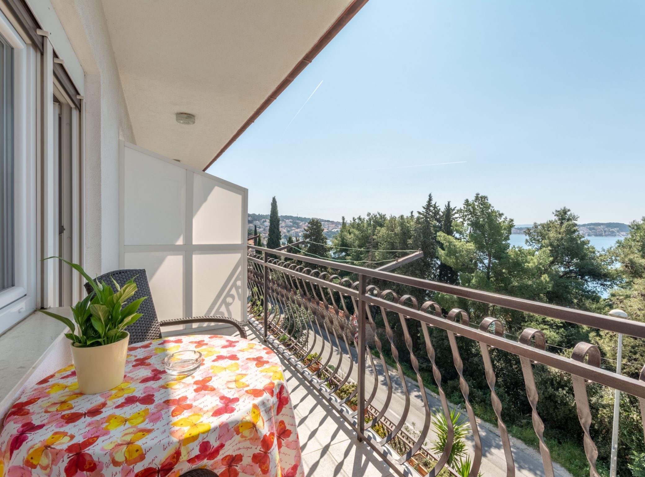 Un balcon avec une table et une chaise, offrant une vue panoramique sur les arbres et l’eau.
