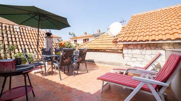 A patio with outdoor furniture, a satellite dish, and a stone wall.