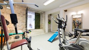 Une salle de sport à domicile équipée de divers appareils d’exercice, notamment un banc, des haltères et un appareil elliptique.