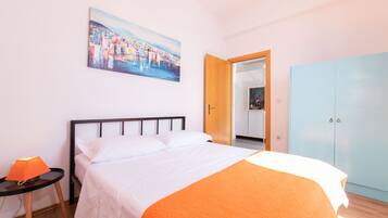 A bedroom with a bed, a nightstand, a painting, and a wardrobe.