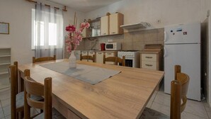 Una cocina compacta con armarios de madera, una mesa con sillas, microondas, estufa y refrigerador.