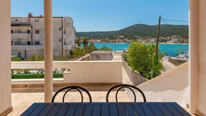 Un balcón con vistas a un pueblo costero, una mesa y sillas.