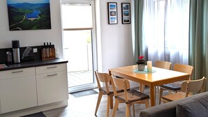 Eine moderne Küche mit Essbereich, einem großen Fenster mit Vorhängen und einem Gemälde an der Wand.