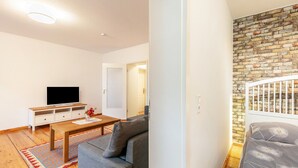 Un salon moderne avec un téléviseur à écran plat, un canapé, une table basse et un mur décoré d’un motif en briques.