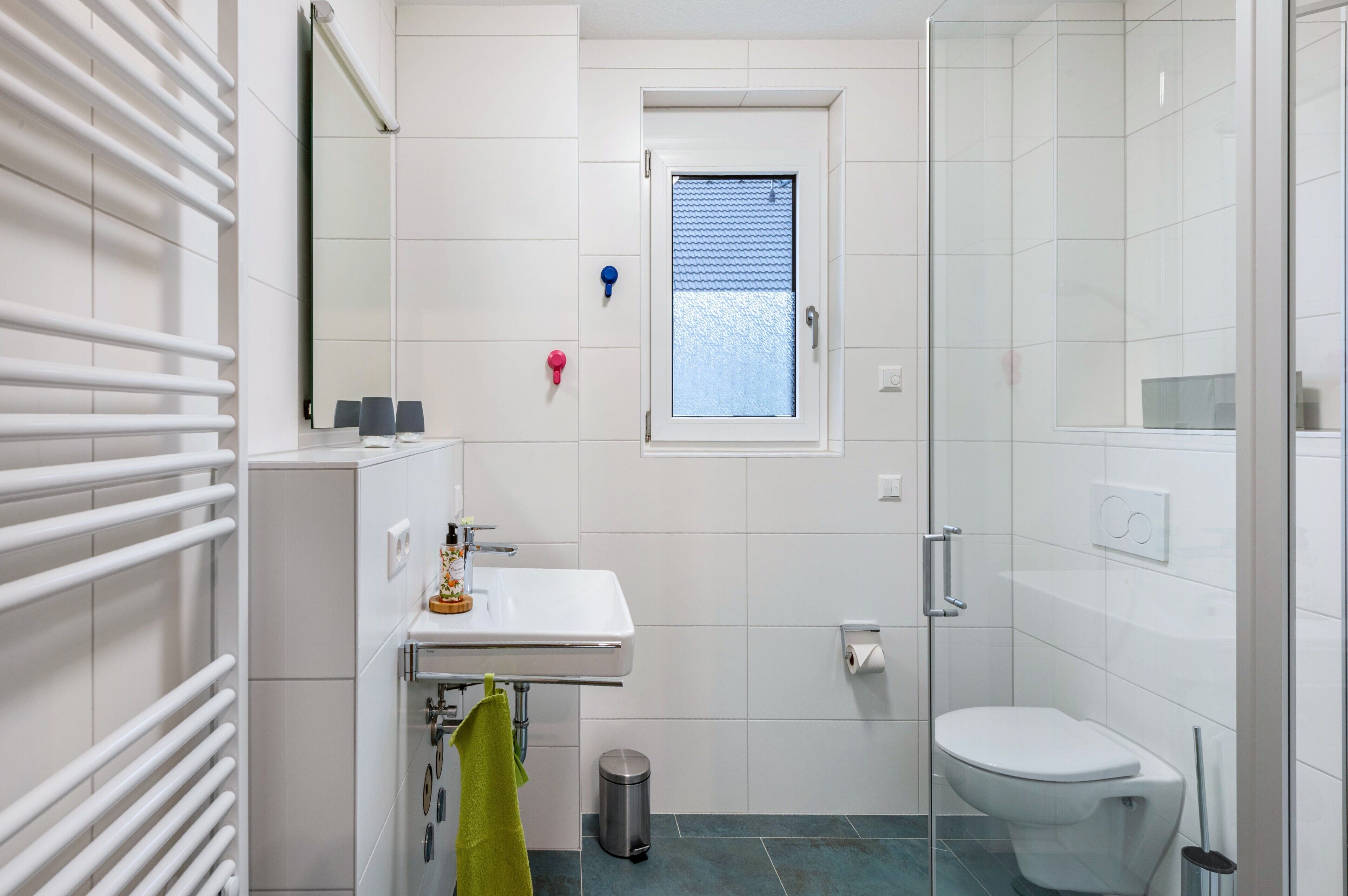 Un baño moderno con lavamanos, espejo y retrete blancos.